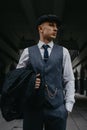 A man posing in the image of an English retro gangster in Peaky blinders style at city street