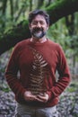 Man posing for nature environment concept picture holding a big dry brown leaf in autumn season. Outdoor adventure leisure