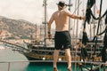 Man posing. Old pirate ship on the water of Mediteranean sea. Tourist entertainment, coastal tour. Summer sunny day. Mountain