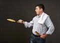Man posing with a pancake in a pan, white shirt and pants, gray background, surprised emotions