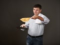 Man posing with a pancake in a pan, white shirt and pants, gray background, surprised emotions