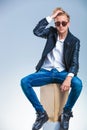 Man posing wearing sunglasses and fixing his hair while sitting Royalty Free Stock Photo