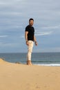 Man posing barefoot on the beach wearing casual a black t-shirt Royalty Free Stock Photo
