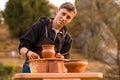 Man potter work with clay ware. Young man potter on his workshop with nature background