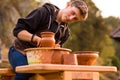 Man potter work with clay ware. Young man potter on his workshop with nature background