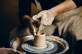 Man potter working on potters wheel making ceramic pot from clay in pottery workshop