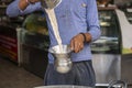 Man pour cup of hot milk tea Indian style or chai for customers in his shop along the street in Pushkar, India Royalty Free Stock Photo