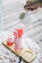 A man pour a milk into a glass of fresh tasty cold milk and ice cube red syrup to make pink milky.Sweet beverage at coffee shop or