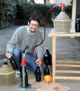 Man pour red wine from the demijohn to glass bottles Royalty Free Stock Photo