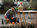 Man pour red wine from the demijohn to glass bottles Royalty Free Stock Photo