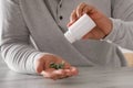 Man pouring antidepressants from bottle at white marble table, closeup