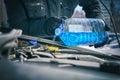 Man pouring an antifreeze liquid in a windshield washer tank of a car