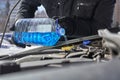 Man pouring an antifreeze liquid in a windshield washer tank of a car Royalty Free Stock Photo