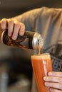 Man pouring a canned drink into a tall glass