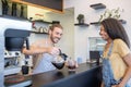 Man pouring coffee at counter and waiting woman