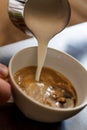 man pouring into a cup of coffee with milk Royalty Free Stock Photo