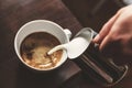 man pouring into a cup of coffee with milk Royalty Free Stock Photo