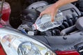 Man pouring distilled water ecological alternative to washing fluid to washer tank in car, detail on hand holding clear Royalty Free Stock Photo