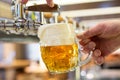 A man pouring draft lager beer into a dimpled glass mug  in a modern pub. Overflowing glass Royalty Free Stock Photo