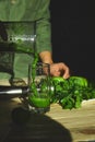 Man pouring in glass healthy detox smoothie, cooking with blender with fresh fruits and greens spinach,