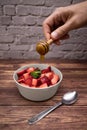 Man pouring honey on fresh strawberries.