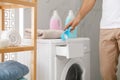 Man pouring laundry detergent into washing machine drawer in bathroom, closeup Royalty Free Stock Photo