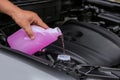 Man pouring liquid from plastic canister into car washer fluid reservoir Royalty Free Stock Photo