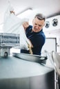 Man pouring malt to brewery equipment for craft beer production.