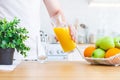 Man pouring orange juice from jug into glass in the kitchen Royalty Free Stock Photo