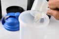 Man pouring protein powder from measuring  into shaker on white table, closeup Royalty Free Stock Photo