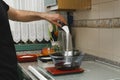 Man pouring sugar in a glass bowl that's on the weighing scale in the kitchen