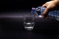 Man is pouring water into the glass, black background, water bottle and glass cup close up Royalty Free Stock Photo