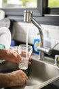 Man pouring water into glass in kitchen Royalty Free Stock Photo