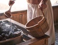 Man pouring water into hot stone in sauna room