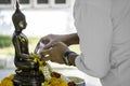 Man pouring water mixed with colourful petal flowers and perfume onto a Buddha image Royalty Free Stock Photo