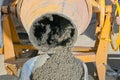 Man pouring wet cement into wheelbarrow close up Royalty Free Stock Photo