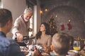 Man pouring wine for family Christmas dinner