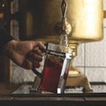 Man pours boiling water from antique copper samovar into modern glass teapot. Retro style. Vintage image. Close up shot Royalty Free Stock Photo