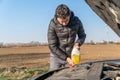 Man pours into the car yellow liquid for the wiper Royalty Free Stock Photo