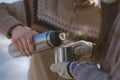 A man pours a hot drink from a thermos into a cup for a woman Royalty Free Stock Photo