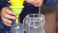 A man pours lavender-infused vodka from a decanter into a bottle. Uses a funnel and a sieve. Lavender tincture at home. Close-up