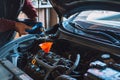 Man pours new oil into the engine through red funnel