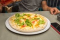Man pours oil on the pizza, focus on lettuce shallow depth of field. The oil is poured on a vegetarian pizza with lettuce and slic