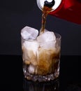 man pours soda from an aluminum red can into a glass with ice, against a dark background. The drink is produced and manufactured Royalty Free Stock Photo