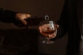 the man pours some brandy into a glass