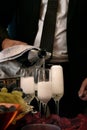 Man pours champagne into wine glasses on a table in the middle of rose petals Royalty Free Stock Photo