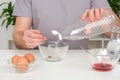 A man pours spoonful vinegar into glass cup with dye. Dyeing eggs with coloring in Easter egg