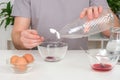 A man pours spoonful vinegar into glass cup with dye. Dyeing eggs with coloring in Easter egg