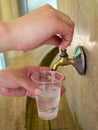 Man pours water on the mineral springs in a plastic cup