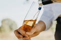 A man pours white wine from a bottle into a transparent glass. Offsite catering in nature with a waiter. Selective focus Royalty Free Stock Photo